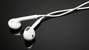 White earbuds with cables lying on a reflective black surface.