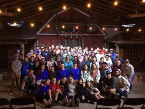 A group of people in blue shirts and black chairs.