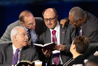 A group of men in suits and ties reading.