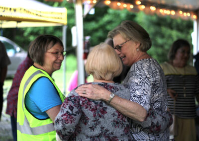 Two women hugging each other while a man stands next to them.