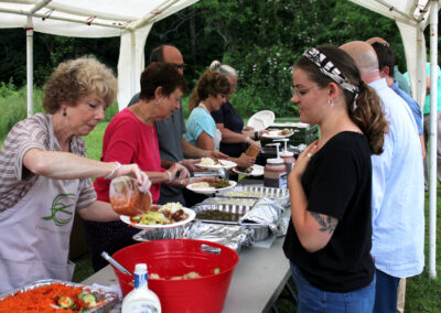 Outdoor potluck serving line under tent