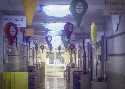 A hallway with many balloons hanging from the ceiling.