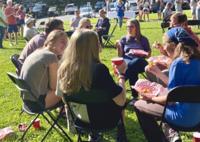 A group of people sitting in chairs on the grass.