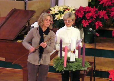 Two women standing next to each other holding candles.