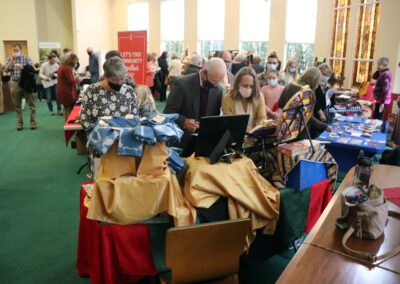 A group of people sitting around tables with bags on them.