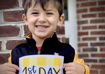 Smiling child holding first day sign