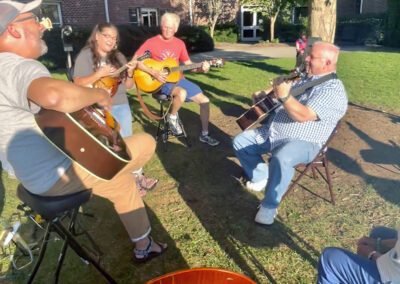Outdoor guitar circle jam on sunny lawn