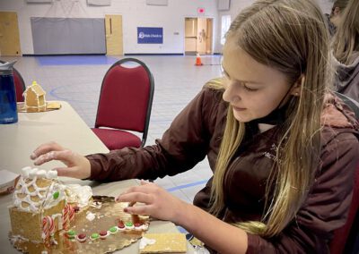 Girl decorating gingerbread house with candy