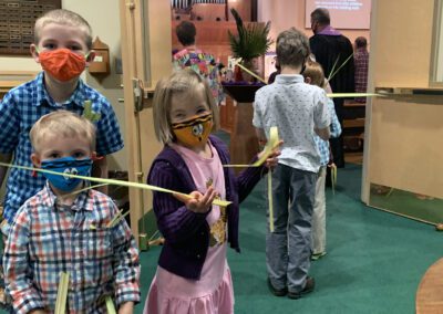 Masked children holding palm branches in church