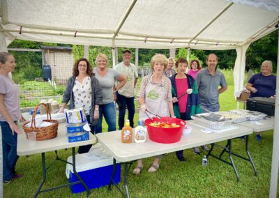 Volunteers serving food under outdoor canopy