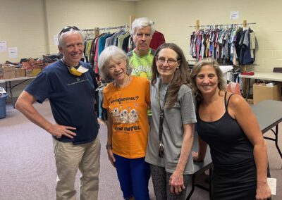 Five volunteers posing in clothing donation room