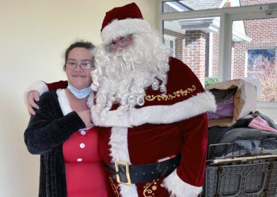 Smiling woman hugging Santa Claus indoors