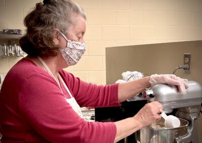 Masked woman pouring ingredients into mixer