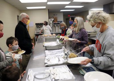 Masked volunteers serving meals at community dinner