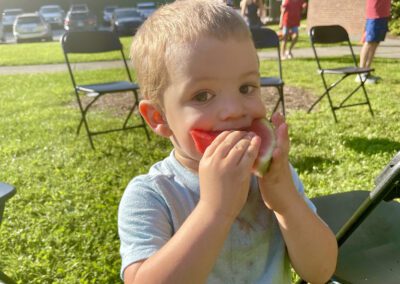 Sunlit toddler biting juicy watermelon slice